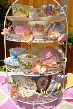 a three tiered plate rack with cups and saucers on it's sides