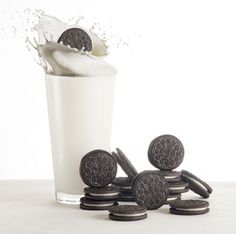 oreo cookies and milk in a glass with splashing milk on the side,