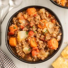 two bowls filled with meat and vegetables on top of a white table next to cornbreads