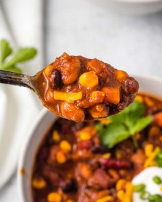 a spoon full of chili with corn and sour cream