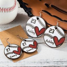 two baseball themed earrings with the number twenty and heart on them, sitting next to a catchers mitt