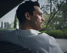 a man sitting on top of a bench next to trees