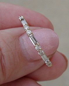 a close up of a person's hand holding a ring with diamonds on it