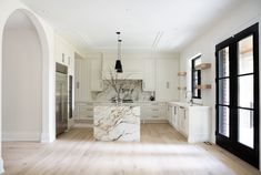 a large kitchen with white cabinets and marble counter tops