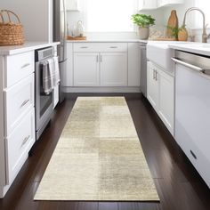 a clean kitchen with white cabinets and wood flooring is seen in this image from the doorway