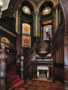 an ornate staircase with stained glass windows and wooden steps leading up to the second floor