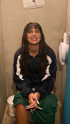 a woman sitting on top of a toilet in a bathroom