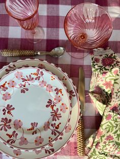 the table is set with pink and white plates, silverware, and napkins