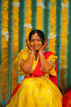 a woman dressed in yellow and red poses for the camera with her hands up to her face