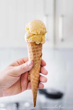 a person holding an ice cream cone in their left hand and the other hand is holding it up