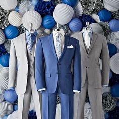 three suits are displayed in front of blue and white paper balls