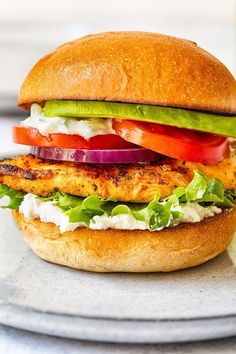 a chicken sandwich with lettuce, tomato and cucumber on a plate