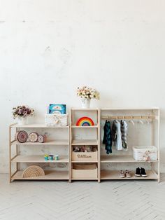 a shelf with clothes, shoes and other items on it in front of a white wall