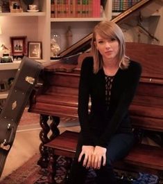 a woman sitting on the floor next to a piano