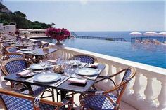 an outdoor dining area with tables and chairs near the water's edge is shown