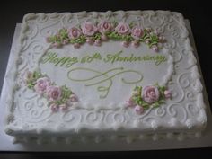 a white cake with pink roses on it and the words happy 50th anniversary written in green