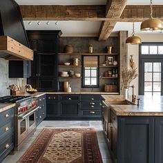 a large kitchen with black cabinets and wooden beams on the ceiling, along with an area rug