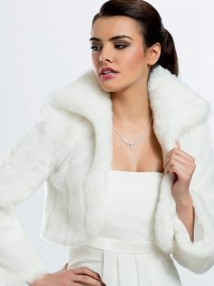 a woman in a white dress and fur coat with her hands on her hips, posing for the camera