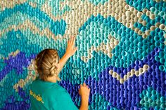 a woman is working on a wall made out of plastic tubes and circles, with her hands in the air