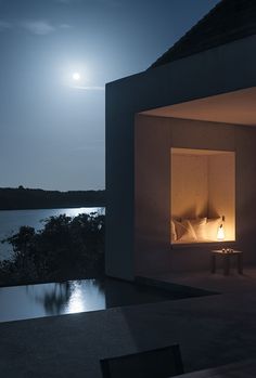 a bed sitting in the middle of a room next to a lake at night time