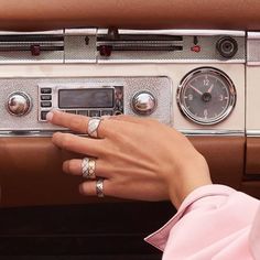 a woman's hand on the dashboard of a car with two rings and an analog clock