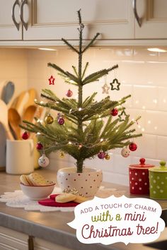 a small christmas tree sitting on top of a kitchen counter next to some cups and saucers