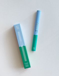 two blue and green toothbrushes sitting next to each other on a white surface