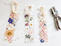 three pairs of scissors and some flowers on a white counter top next to each other