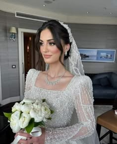 a woman in a wedding dress holding a bouquet of flowers and wearing a tiara