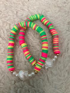 three bracelets with colorful beads and pearls on a white carpeted surface in the background