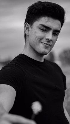 a black and white photo of a man holding a flower