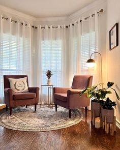 a living room with two chairs and a rug in front of the window, next to a lamp