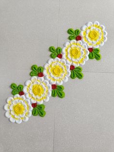 a white and yellow flower design on the floor with green leaves, red berries and flowers