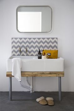 a bathroom sink sitting under a mirror next to a white towel on top of a wooden table