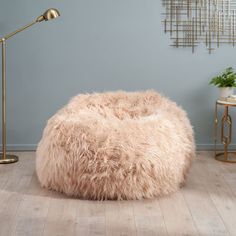 a large furry bean bag chair sitting on top of a hard wood floor next to a lamp