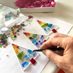 someone is making stained glass christmas trees out of scrapbook paper and colored pencils