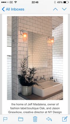 a bathroom with white tiles and a plant on the counter in front of the mirror