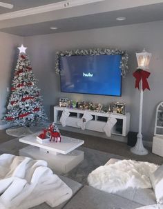 a living room decorated for christmas with white furniture and red decorations on the tv screen