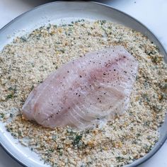 a piece of raw fish sitting on top of a white plate covered in seasoning