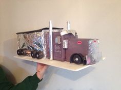 a cake shaped like a semi truck is being held up by a woman's hand