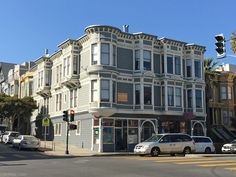 an old building on the corner of a street with cars parked in front of it