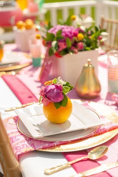 an orange sitting on top of a white plate next to a pink and yellow table cloth