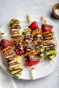 a white plate topped with fruit and chocolate covered skewers