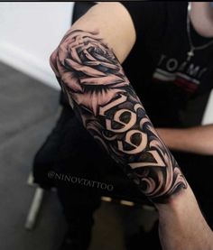 a man with a black and white rose tattoo on his arm that says love in cursive lettering