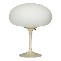 a table lamp with a white shade on it's base and a black cord attached to the bulb