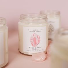 some candles are sitting next to each other on a pink surface with one candle in the middle