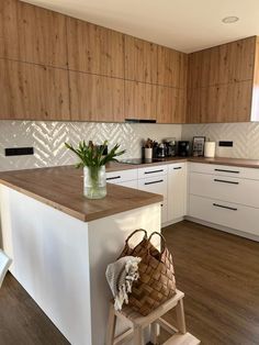 a kitchen with wooden floors and white cabinets, a basket on the counter top next to a stool