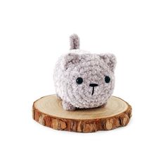 a crocheted stuffed animal sitting on top of a wooden stump in front of a white background