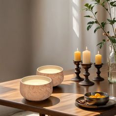 a wooden table topped with bowls and candles