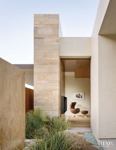 an entrance to a modern home with plants in the foreground and a chair on the far side